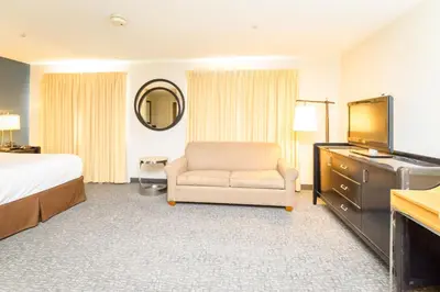 a hotel room with a bed and a chair and a television at Philadelphia Suites at Airport - An Extended Stay Hotel in Philadelphia