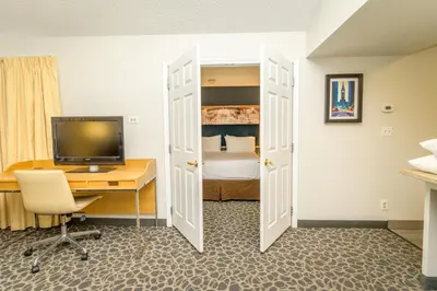 a room with a desk and a computer and a bedroom at Philadelphia Suites at Airport - An Extended Stay Hotel in Philadelphia