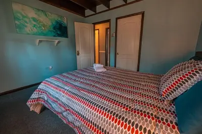 a bedroom with a large bed with a colorful comforter at Cheerful Chalet - Fireplace, BBQ, Firepit& Hottub in Long Pond