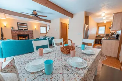 a living room with a table with plates on it at PoconoChalet-Hot Tub-Grill-Firepit-Games in Long Pond