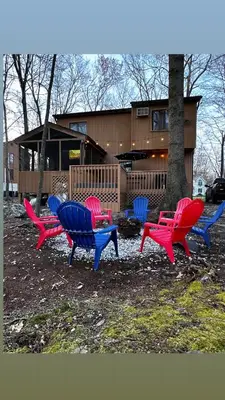 a group of colorful chairs in front of a house at Cozy Cabin at Poconos With Hot Tub and Fire Pit in East Stroudsburg