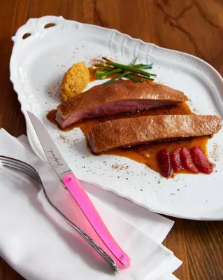 a plate of food with meat and bacon on a table at The Ludlow Hotel in New York