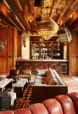 a bar with brown leather couches and a bar with a bar at The Ludlow Hotel in New York