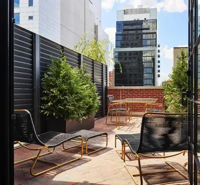 a group of chairs and tables on a balcony at The Ludlow Hotel in New York