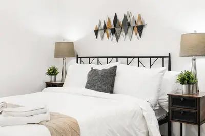 a bedroom with a bed with white sheets and pillows at Stylish 3BR Philly Retreat with Free Parking in Philadelphia