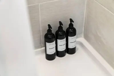 three black bottles sitting on the corner of a bath tub at Stylish 3BR Philly Retreat with Free Parking in Philadelphia