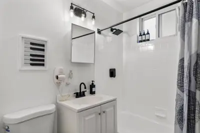 a white bathroom with a sink and a shower at Stylish 3BR Philly Retreat with Free Parking in Philadelphia