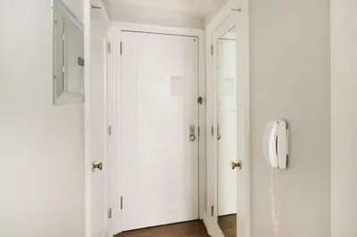 a hallway with a white door and a phone at 73-519 New Studio UWS Doorman Gym in New York