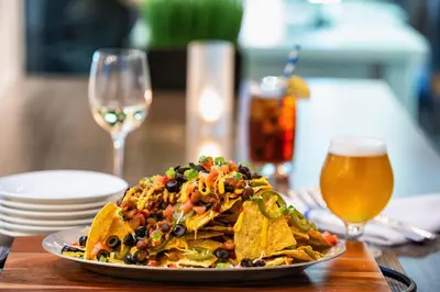 a plate of nachos on a table with a glass of beer at Element Harrison-Newark in Harrison