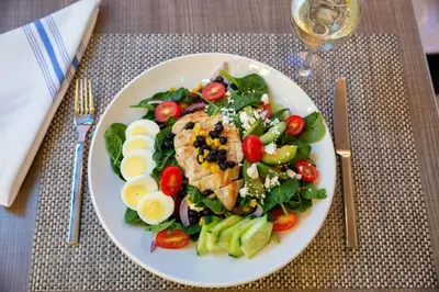 a white plate with a salad with chicken and vegetables at Element Harrison-Newark in Harrison
