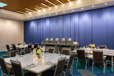 a conference room with tables and chairs in front of a blue wall at Element Harrison-Newark in Harrison