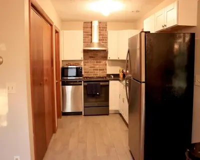 a kitchen with a black refrigerator and white cabinets at Rosie’s Cabin in Thornhurst