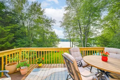 a wooden deck with a wooden table and chairs at 11 Mi to Slopes! Poconos Lake House with Beach in Pocono Summit