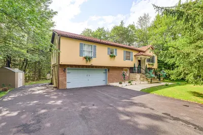 a house with a garage on a driveway at 11 Mi to Slopes! Poconos Lake House with Beach in Pocono Summit