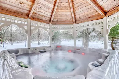 a hot tub in a gazebo in the snow at Antler Ridge: 3BDR w Hot Tub & Game Room in Albrightsville