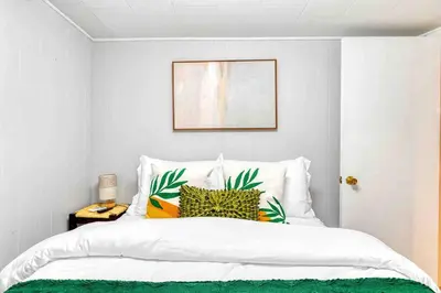 a bedroom with a white bed with a green and yellow pillow at Hot Tub Fire Pit Dog Friendly in Pocono Lake