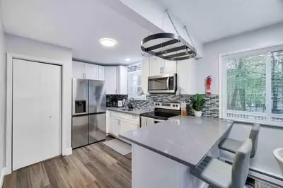a kitchen with white cabinets and a stainless steel refrigerator at Cozy, Spacious House *New*InTheCommunity+Fire Pit in Tobyhanna