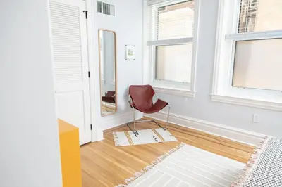 a chair in a room with white walls and windows at The Suites at the Touraine No 109 in Philadelphia