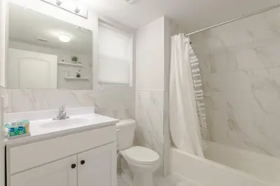 a white bathroom with a sink and a toilet and a tub at Modern one bedroom apartment in Elizabeth