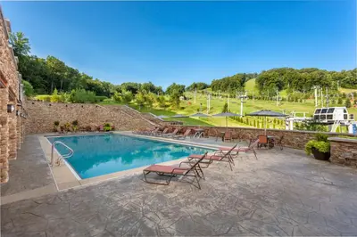 a swimming pool with chairs and a table at Bear Creek Mountain Resort in Breinigsville