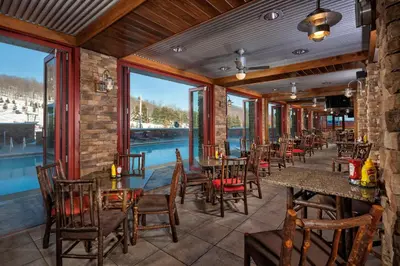 a restaurant with tables and chairs and a pool at Bear Creek Mountain Resort in Breinigsville