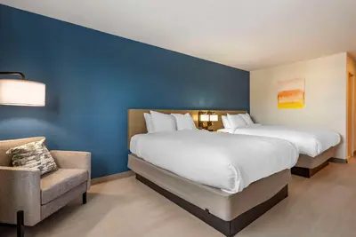 a hotel room with two beds and a chair at Comfort Inn Philadelphia International Airport West in Chester