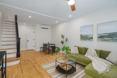 a living room with a green couch and a table at Modern + Airy Fishtown Townhouse w/ Arcade in Philadelphia