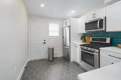 a kitchen with white cabinets and a stove top oven at Modern + Airy Fishtown Townhouse w/ Arcade in Philadelphia