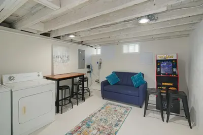 a living room with a blue couch and a kitchen at Modern + Airy Fishtown Townhouse w/ Arcade in Philadelphia