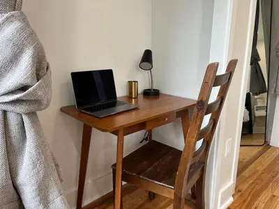 a laptop computer sitting on a wooden desk with a chair at Modern + Airy Fishtown Townhouse w/ Arcade in Philadelphia