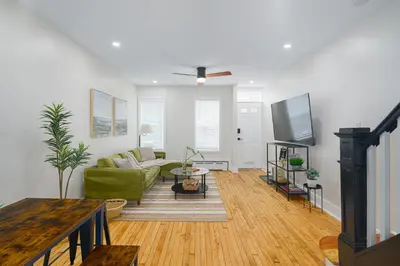 a living room with a green couch and a table at Modern + Airy Fishtown Townhouse w/ Arcade in Philadelphia