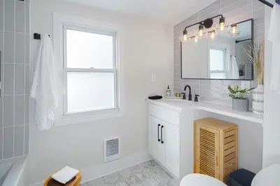 a white bathroom with a sink and a mirror at Modern + Airy Fishtown Townhouse w/ Arcade in Philadelphia