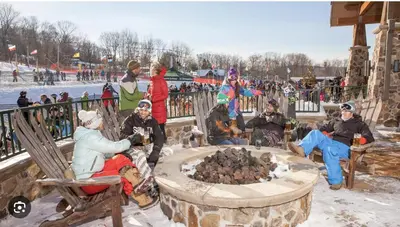 a group of people sitting around a fire pit in the snow at Cozy Mountain View Condo in Vernon Township