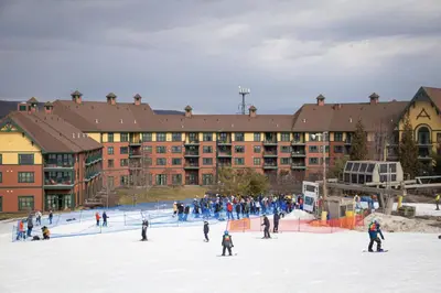 a group of people skiing in the snow in front of a building at Cozy Mountain View Condo in Vernon Township