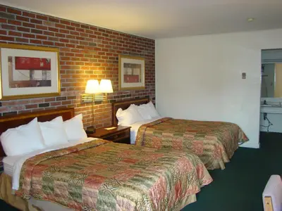 a hotel room with two beds and a brick wall at Aderi Hotel Lewisburg in Lewisburg