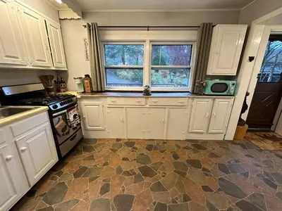 a kitchen with white cabinets and a tile floor at Escape to a Streamside Cabin in the Lower Catskills in Wurtsboro