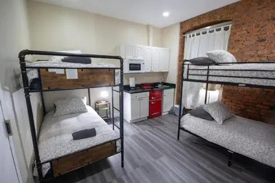 a small room with three bunk beds and a kitchen at STUDIOPLUS by JGSTAY, Midtown ESB in New York