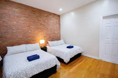 a bedroom with two beds and a brick wall at STUDIOPLUS by JGSTAY, Midtown ESB in New York