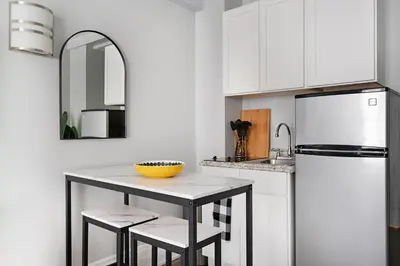 a kitchen with a white refrigerator and a table with stools at 73-1204 New Studio UWS Doorman Gym in New York