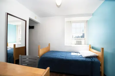 a bedroom with a bed and a mirror and a table at West Side YMCA in New York