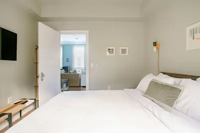 a bedroom with a white bed and a living room at Airy Greenwich Retreat with Private Deck in New York