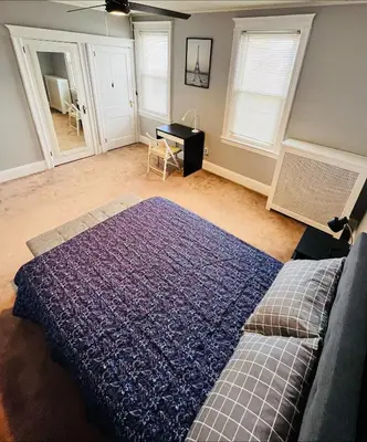 a bedroom with a bed and a table and windows at Cozy Home close to New York City in Fairview