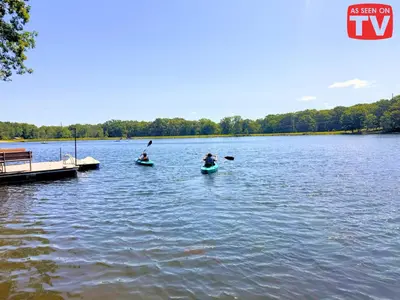 two people in kayaks on a lake with a dock at Lakefront, Pool, Hot Tub, Boats, Game Room, Pets in Bushkill