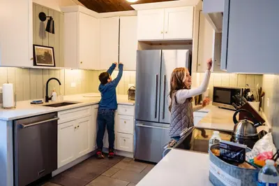 two women standing in a kitchen with their hands in the air at Lakefront, Pool, Hot Tub, Boats, Game Room, Pets in Bushkill