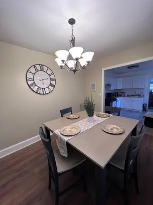 a dining room table with chairs and a clock on the wall at Cozy on the Hill in Wilmington