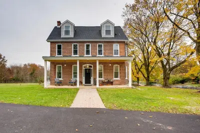a large brick house with a porch on a grass field at Family-Friendly Hatfield Home 3 Mi to Downtown! in Hatfield