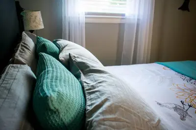 a bed with green pillows on it with a window at Home away from home in Pottstown
