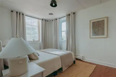 a white bedroom with a bed and a lamp at 1900's Historic Lancaster School House in Willow Street