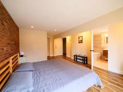 a bedroom with a bed and a brick wall at Stylish 3 bed, minutes to NYC! in Jersey City