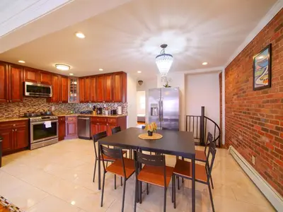 a kitchen with a table and chairs and a brick wall at Stylish 3 bed, minutes to NYC! in Jersey City